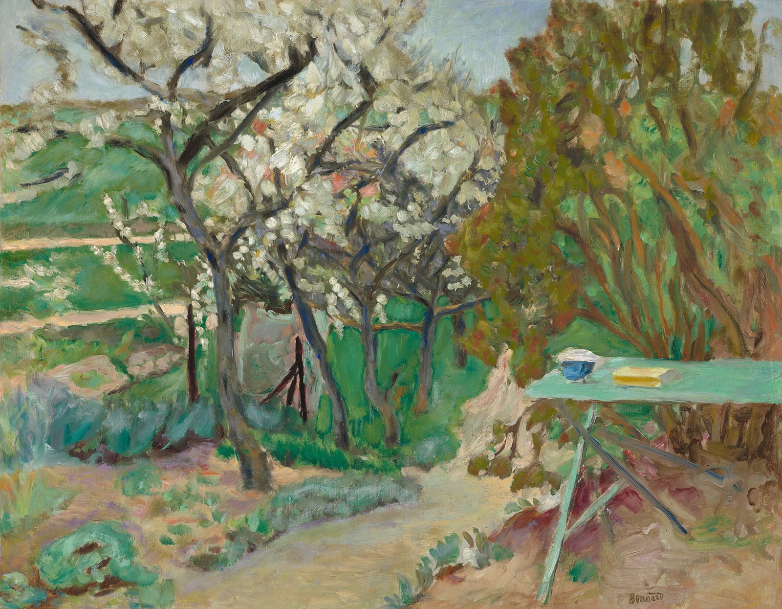 A painting of a green table sitting in a somewhat arid looking garden. There is a row of trees in blossom lining a dirt path leading off into the background. A blue bowl and a yellow book sit on the table, inviting you to sit down.